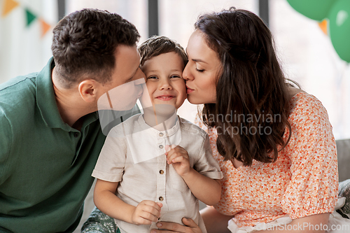 Image of happy parents kissing little son at birthday party