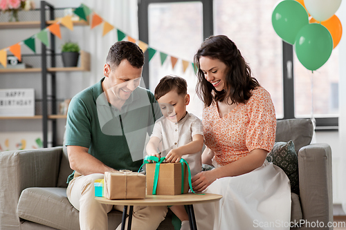 Image of happy family opening birthday presents at home