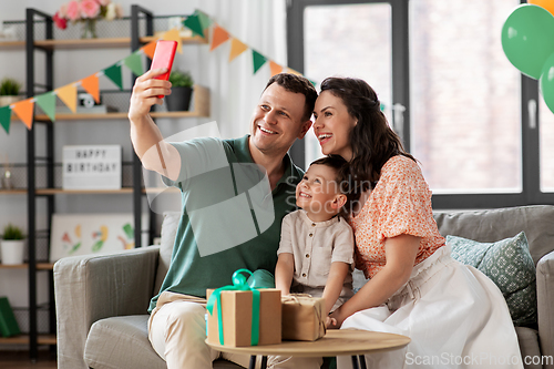 Image of happy family taking selfie on birthday at home