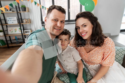 Image of happy family taking selfie on birthday at home