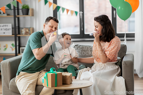 Image of happy family with gifts and party blowers at home