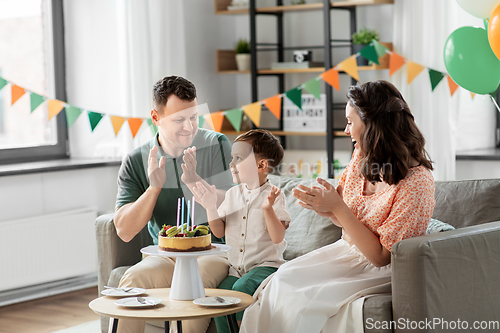 Image of happy family with birthday cake at home