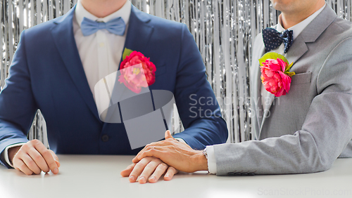 Image of close up of happy male gay couple holding hands