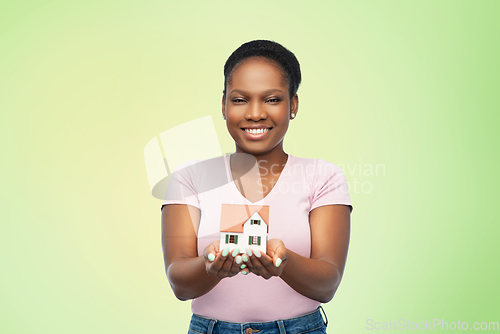 Image of smiling african american woman holding house model