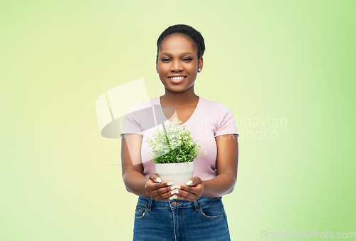 Image of happy smiling african woman holding flower in pot