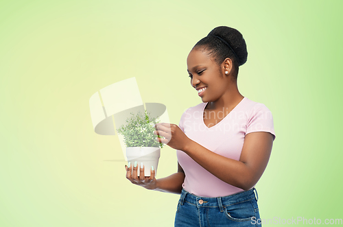 Image of happy smiling african woman holding flower in pot