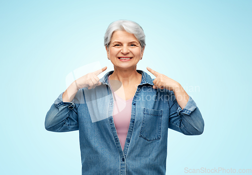 Image of smiling senior woman showing to her face