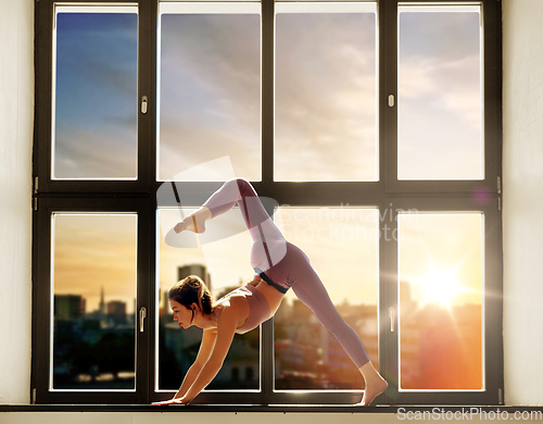 Image of woman doing yoga exercise on window sill at studio