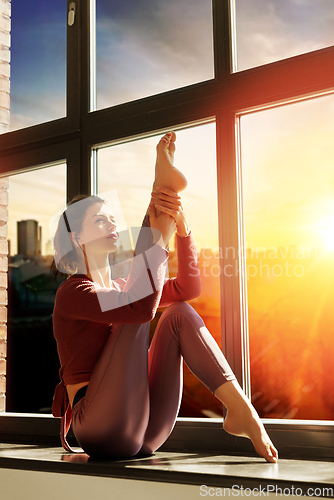 Image of woman doing yoga exercise on window sill at studio