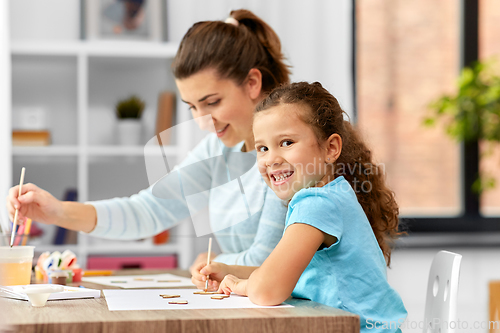 Image of happy mother with little daughter drawing at home