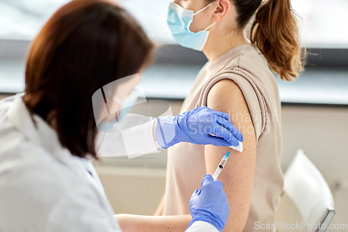 Image of female doctor with syringe vaccinating patient