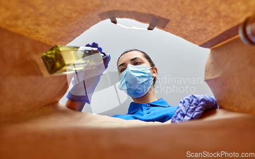 Image of woman in gloves and mask with food in paper bag