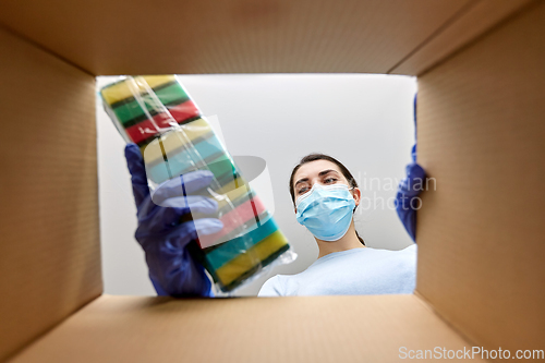 Image of woman in mask taking cleaning supplies from box