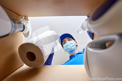 Image of woman in mask packing cleaning supplies in box