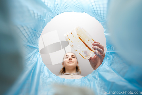 Image of woman throwing plastic container into trash can