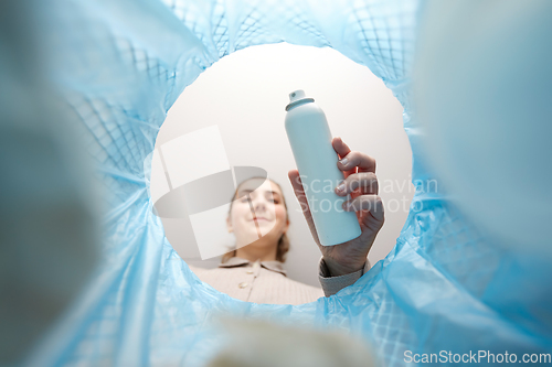 Image of woman throwing hair spray bottle into trash can