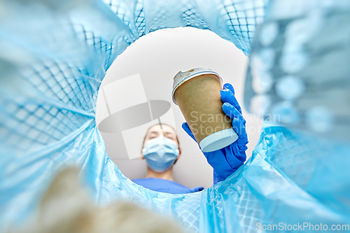 Image of female doctor throwing coffee cup into trash can