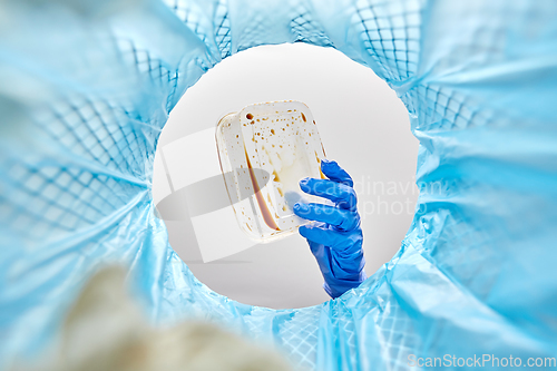 Image of hand throwing plastic container into trash can