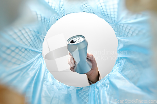 Image of hand throwing tin can into rubbish bin