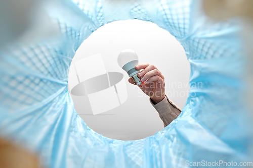 Image of hand throwing light bulb into trash can