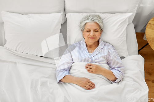 Image of happy senior woman sleeping in bed at home bedroom