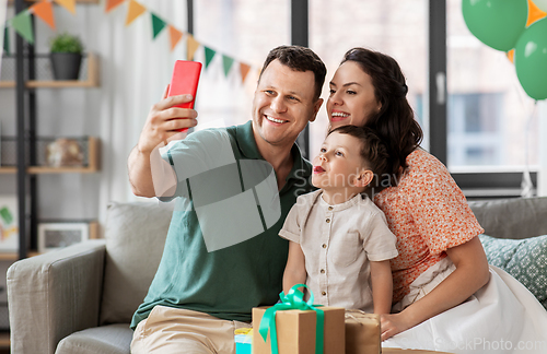 Image of happy family taking selfie on birthday at home