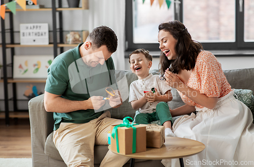 Image of happy family with gifts and party blowers at home