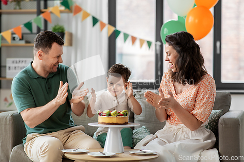 Image of happy family with birthday cake at home party