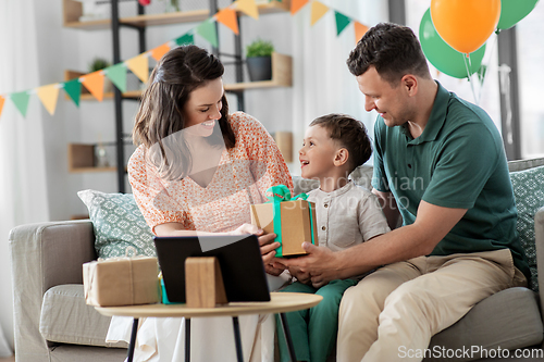 Image of happy family giving present to little son at home