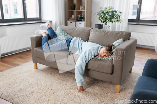 Image of young man sleeping on sofa at home