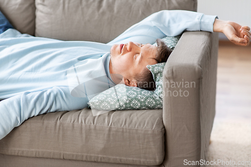 Image of young man sleeping on sofa at home