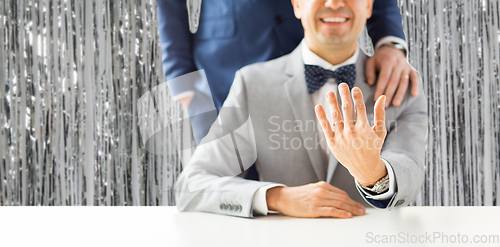 Image of close up of male gay couple with wedding rings on