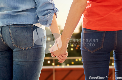 Image of close up of lesbian couple holding hands at party