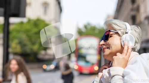 Image of old woman in headphones listens to music in london