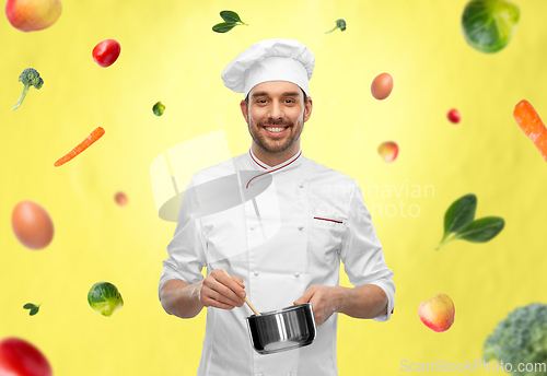 Image of happy smiling male chef with saucepan cooking food