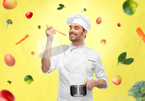 Image of happy smiling male chef with saucepan tasting food