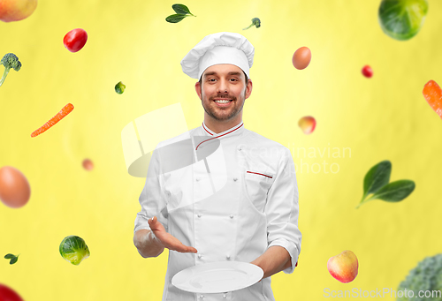 Image of happy smiling male chef holding empty plate