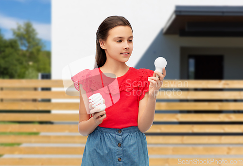 Image of smiling girl comparing different light bulbs