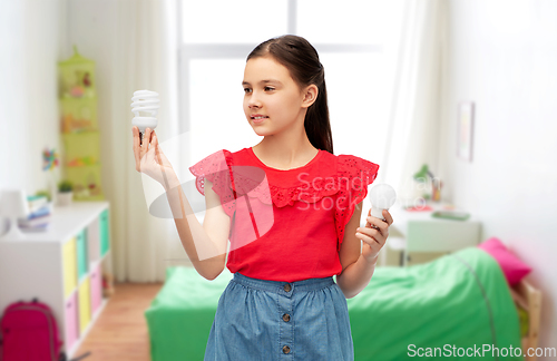 Image of smiling girl comparing different light bulbs