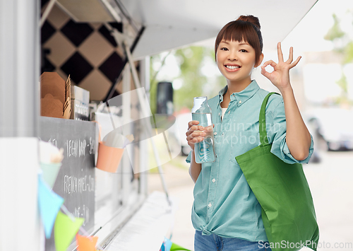 Image of woman with shopping bag and bottle over food truck