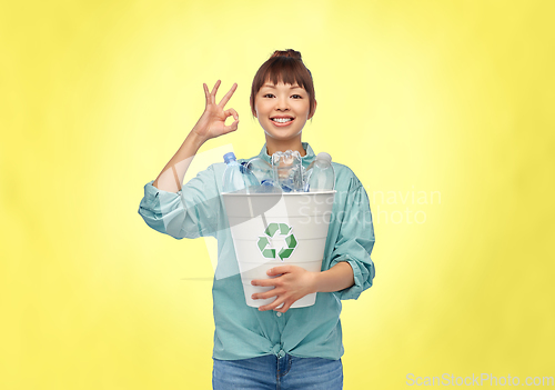 Image of smiling young asian woman sorting plastic waste