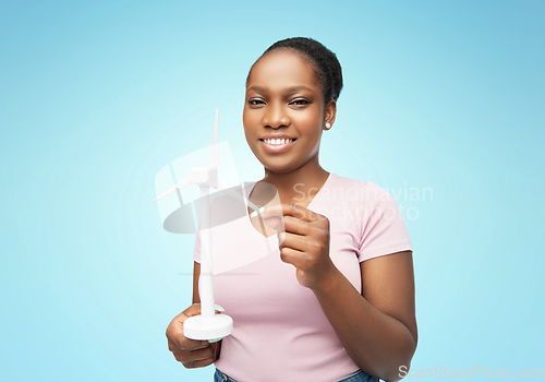 Image of happy african american woman with toy wind turbine