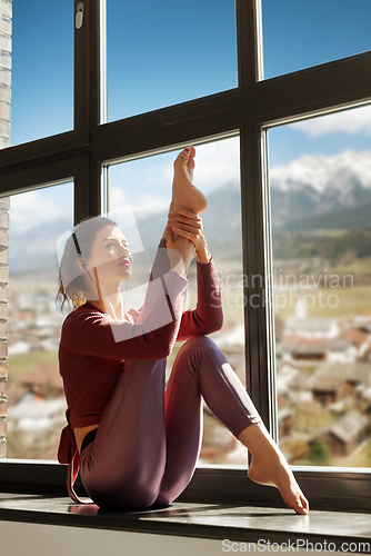 Image of woman doing yoga exercise on window sill at studio