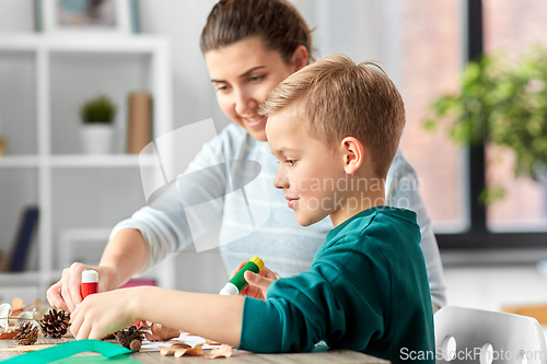 Image of mother and son making pictures of autumn leaves