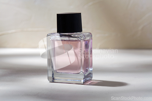 Image of bottle of perfume on white surface with shadows