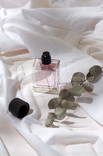 Image of bottle of perfume and on white sheet