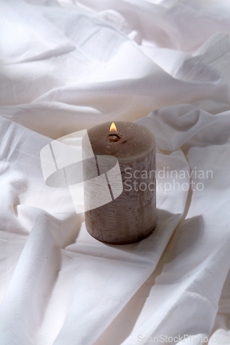 Image of burning aroma candle on white sheet