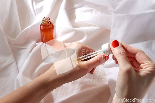 Image of female hands with dropper applying serum to skin