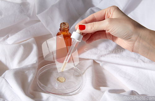 Image of female hand with dropper applying serum to glass