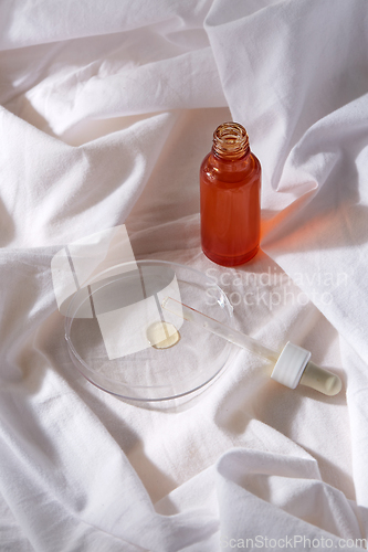 Image of bottle of serum and dropper on white sheet